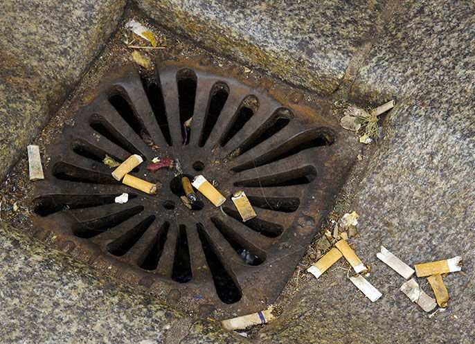 Cigarette butts discarded by a drain