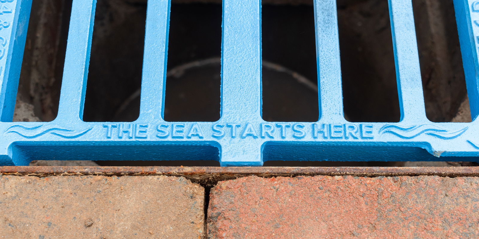 Blue gully grating with the text 'The sea starts here'