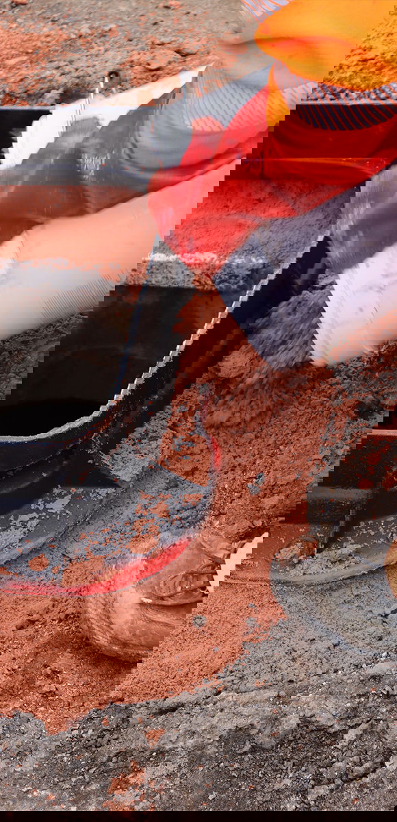 A worker pouring Unipak bedding mortar onto a manhole cover frame