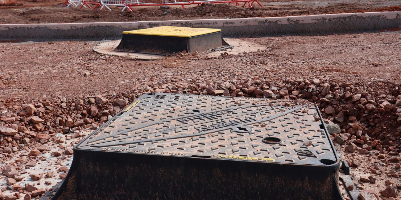 Bespoke Armadillo Manhole Protector Shell installed while one cover remains uncovered
