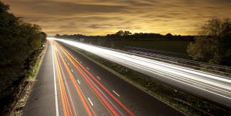 Dark night road with lights showing cars traveling