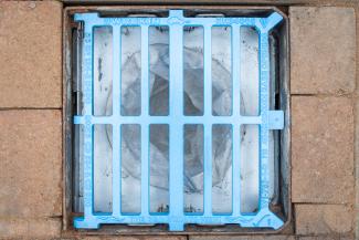 Armadillo Silt Shield installed inside a blue The Sea Starts Here campaign gully grating